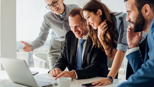 Businesspeople meeting around a laptop.