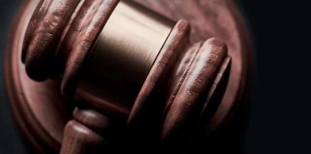 Brown gavel with gold trim on a black background