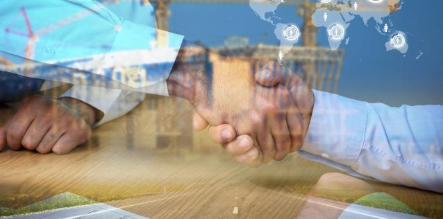 Two hands shaking at a port with map in background