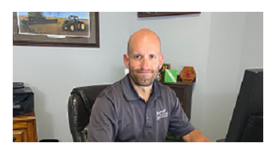 Bald man sitting on a desk working at a computer